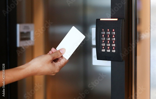 Bild auf Leinwand Door access control - young woman holding a key card to lock and unlock door