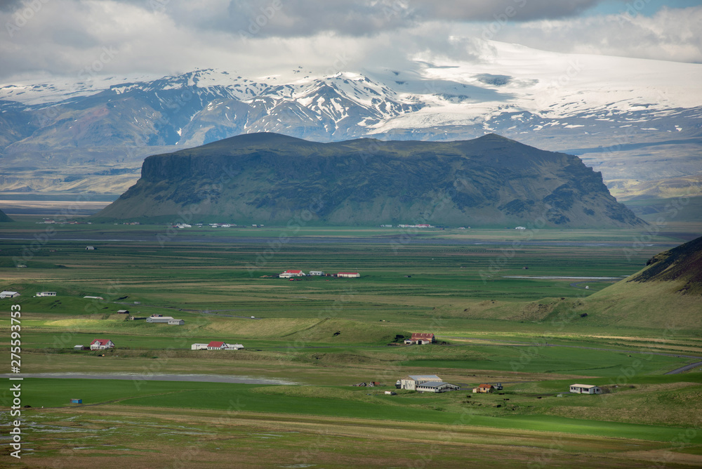 Icelandic landscape with volcanic lava ridge, glacier mountains, green grass. Vik area, Iceland