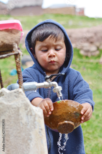 Little latin boy washing plate in the countryside. © ruslanita
