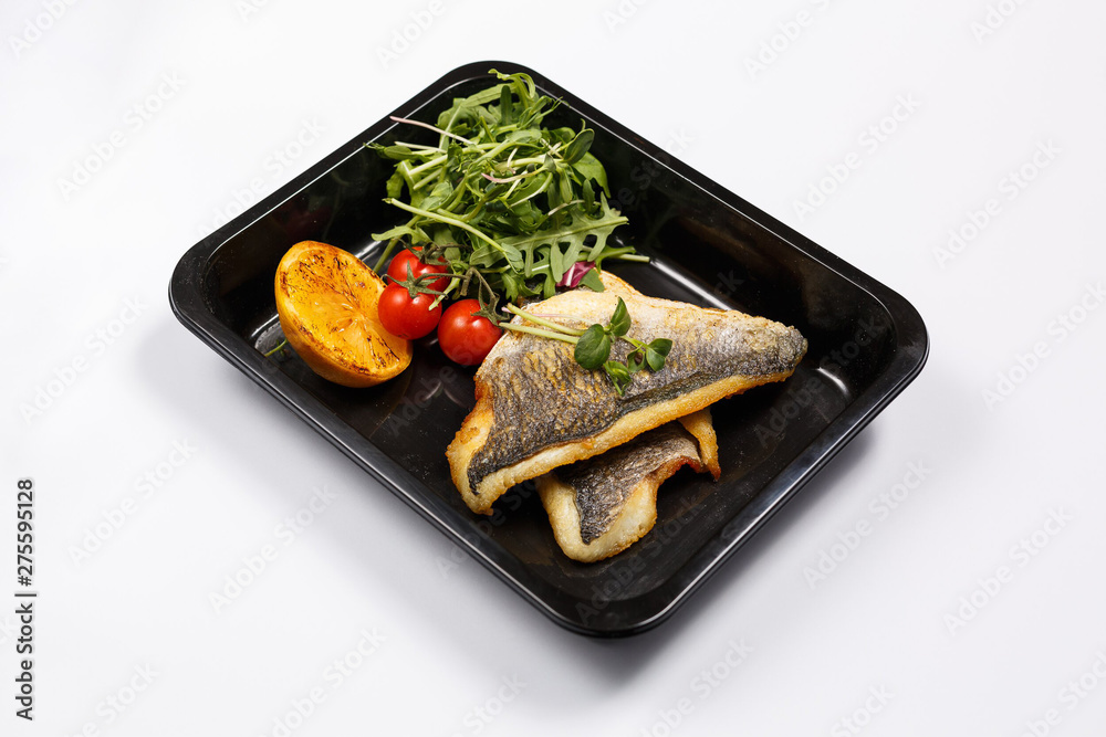 Isolated dish of cooked white fish with cherry tomatoes and arugula. Asian seafood concept. Isolated dish of cooked white fish with cherry tomatoes and arugula. Asian seafood concept.