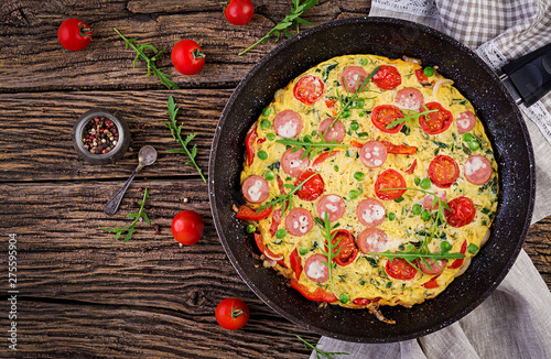 Omelette with tomatoes, sausage and green peas  in rustic style.  Frittata - italian omelet. Top view