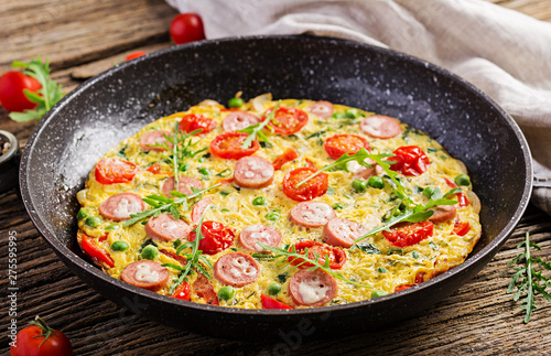 Omelette with tomatoes, sausage and green peas  in rustic style.  Frittata - italian omelet.