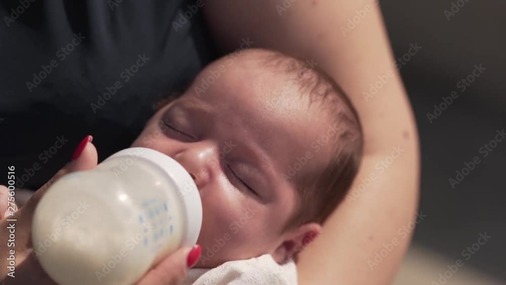 Young beautiful mother is feeding her little baby with a bottle of a milk . Young beautiful mother is feeding her little baby with a bottle of a milk .