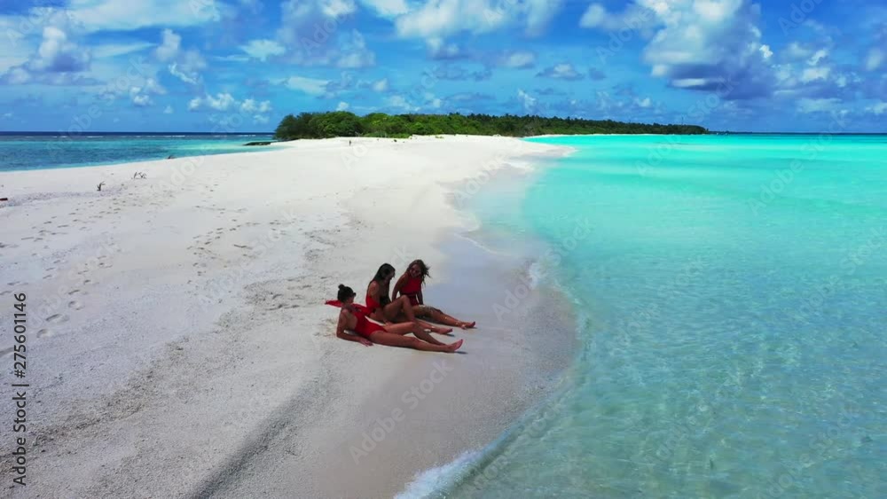 Three models in bikini laying on a white sand beach on a tropical island in the Caribbean and getting tanned Three models in bikini laying on a white sand beach on a tropical island in the Caribbean and getting tanned