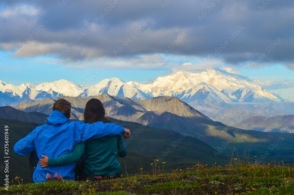 Couple watching a morning view of Mount Denali - mt Mckinley peak during golden hour from Stony Dome overlook. Denali National Park