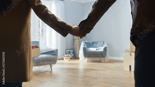 Excited Young Couple Holding Hands Enters Newly Purchased / Rented Apartment. Bright Modern Home for Happy Young People.