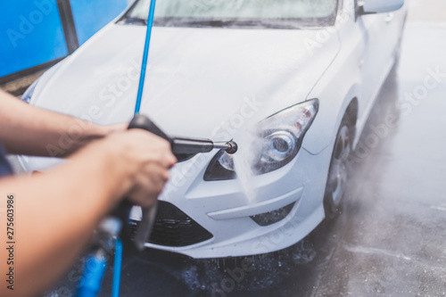 Close up of man hand washing car with pressure washer outdoors.