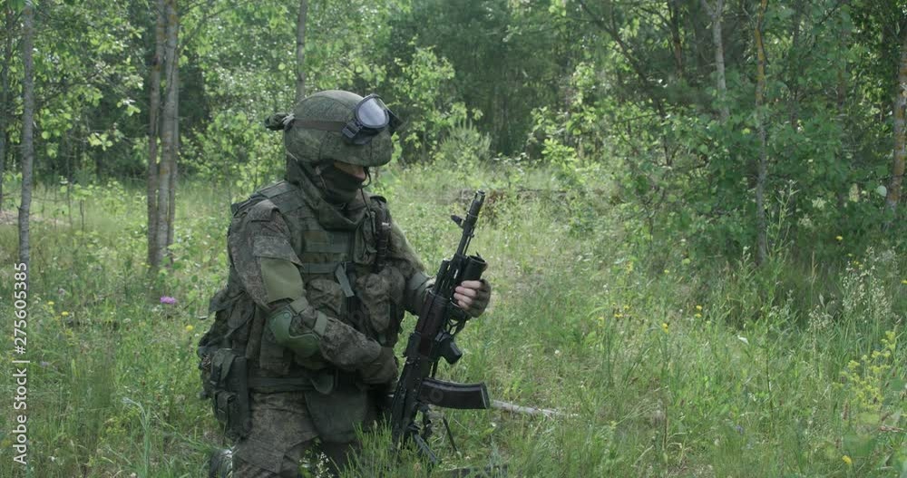 Soldier in camouflage equips a grenade launcher shell in assault rifle, military action in forest. Soldier in camouflage equips a grenade launcher shell in assault rifle, military action in forest.