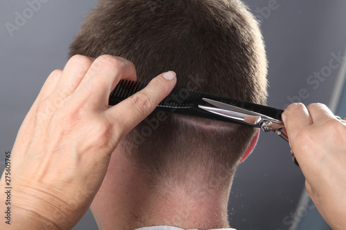 Close-up, master hairdresser does hairstyle with scissors and comb