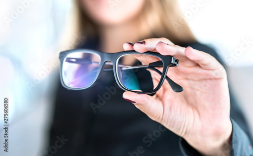 Optician, optometrist, oculist or eye doctor holding glasses and specs with new lenses. Professional eyesight specialist in clinic or shop with spectacles in hand. Bifocal or multifocal eyeglasses. photo