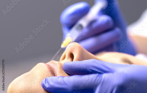 Konstfotografi Close up of lip augmentation with injection needle in beauty salon or plastic surgery clinic by doctor