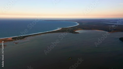 Aerial, reverse, drone shot, high, overlooking the coast of Culburra Beach, at dusk, on a sunny evening, in New South Wales, Australia photo