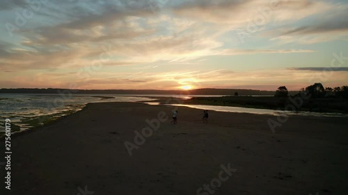 Aerial, reverse, drone shot a couple hugging a third guy, on the beach at sunset, on Culburra Beach, on a sunny evening, in New South Wales, Australia photo