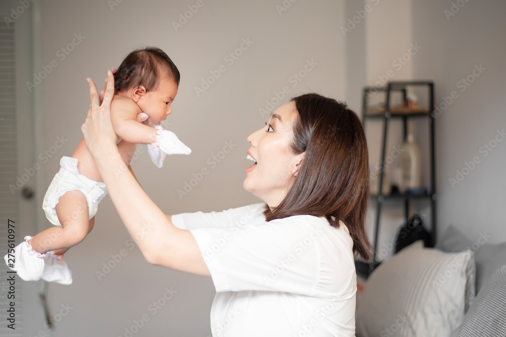 Beautiful mother is playing with her newborn baby in the bedroom. Beautiful mother is playing with her newborn baby in the bedroom.