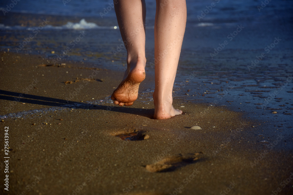 Woman legs on sandy beach. Girl walking on sand by the sea. Beach travel - Summer vacations concepts Woman legs on sandy beach. Girl walking on sand by the sea. Beach travel - Summer vacations concepts