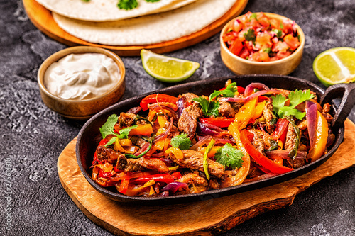 FAJITAS with colored pepper and onions, served with tortillas.