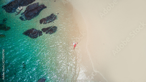 Beach drone view Phuket tropical island, white beach with waves, couple lying on the beach. Aerial Photo.