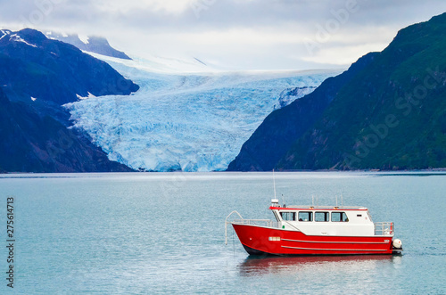 Distant view of a Holgate glacier with red boat in the foreground in Kenai fjords National Park, Seward, Alaska, United States, North America