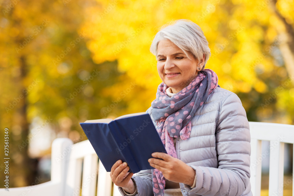 old age, retirement and people concept - happy senior woman sitting on bench and reading book at autumn park old age, retirement and people concept - happy senior woman sitting on bench and reading book at autumn park
