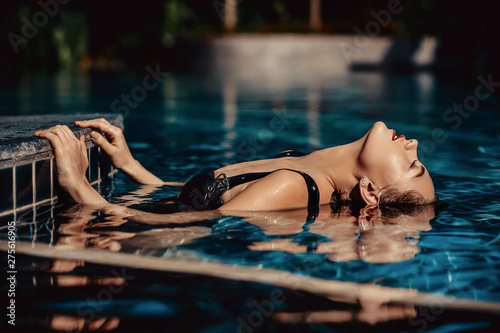 Travel vacation wallpaper - Beautiful young blonde girl in  black bikini with perfect sport sexy body relax in tropical  resort pool at sunny day bungalow.