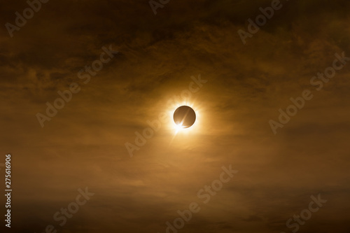 Total solar eclipse in dark red cloudy sky photo