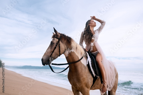 Young brunette beauty having fun and riding horse on the beach © Detkov D