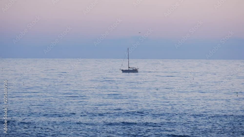 Sailing yacht on ocean at dusk with pink sky Sailing yacht on ocean at dusk with pink sky