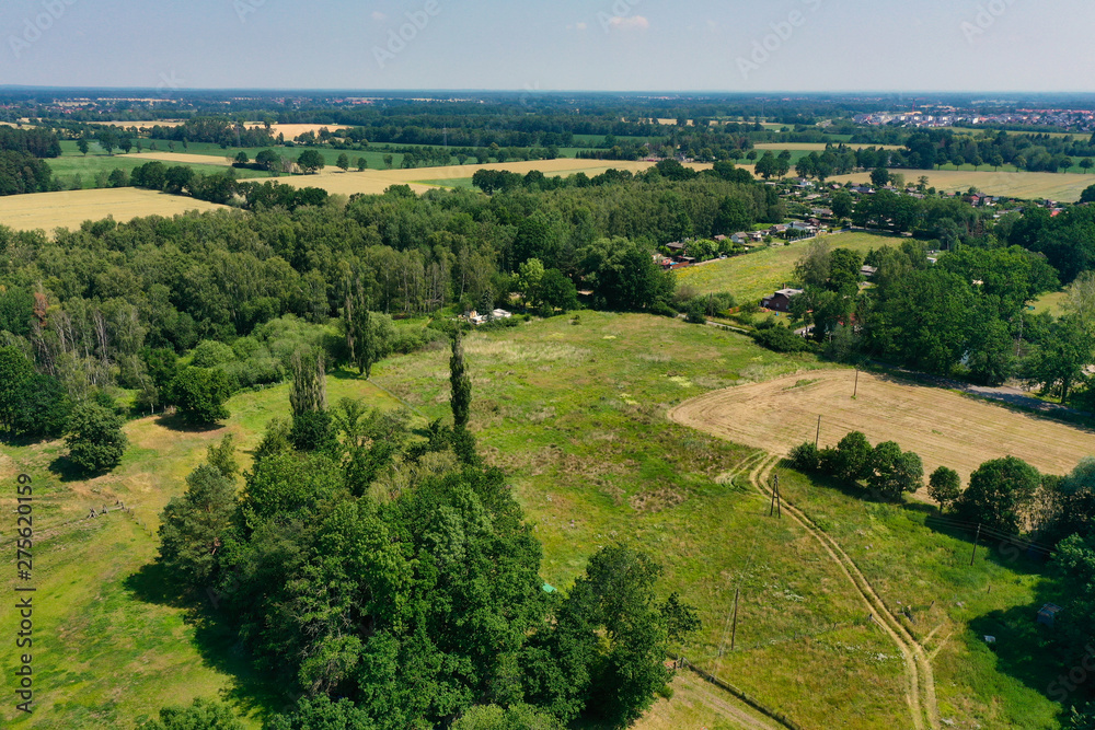 Aerial view of a meadow area with a few houses and a loose stock of bushes and trees. Aerial view of a meadow area with a few houses and a loose stock of bushes and trees.
