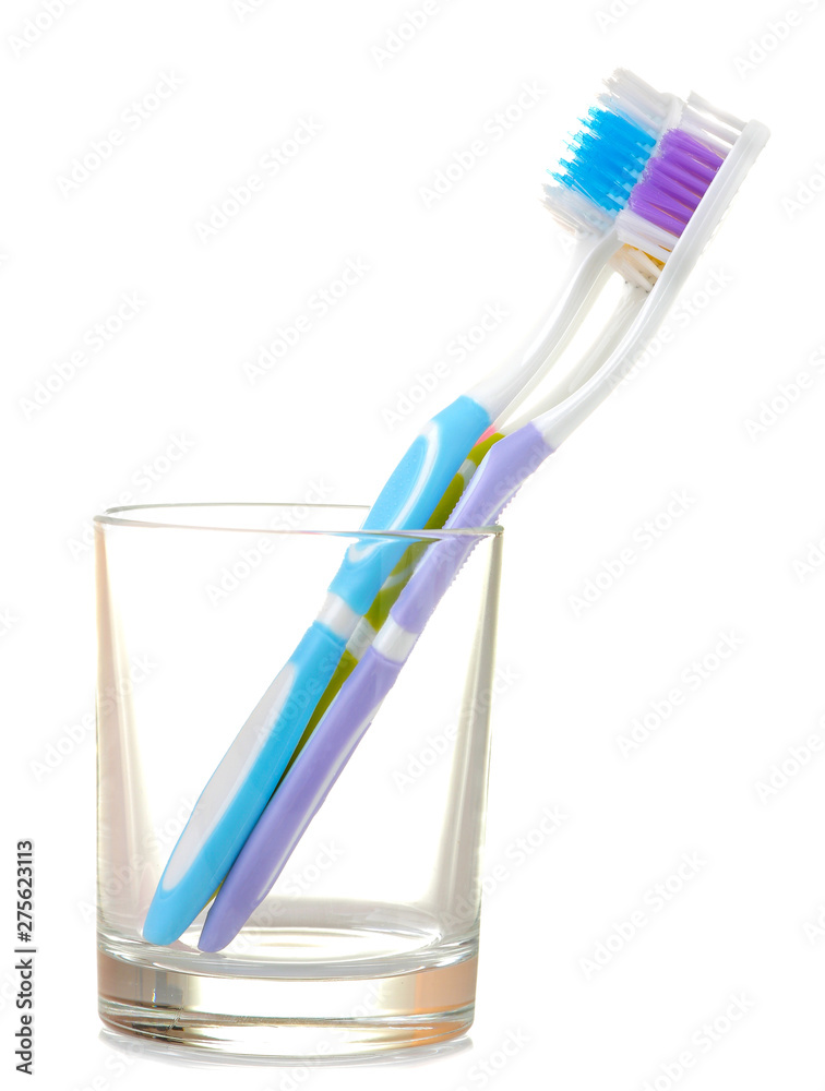 Multi-colored toothbrushes in a glass beaker on a white isolated background. Oral hygiene.