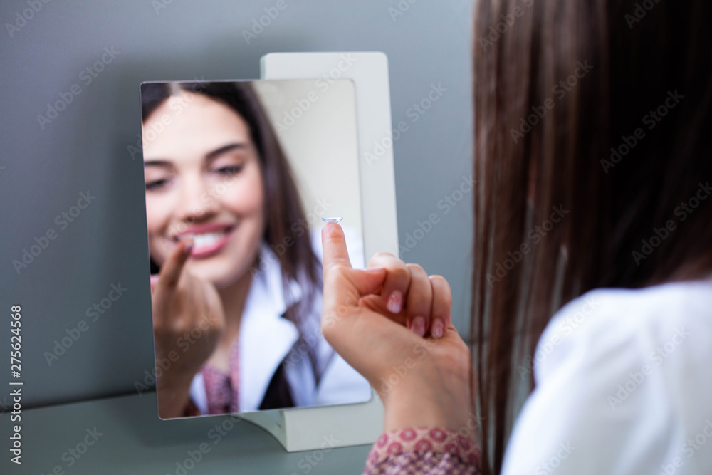 Young woman putting contact lens in her right eye, close up Young woman putting contact lens in her right eye, close up