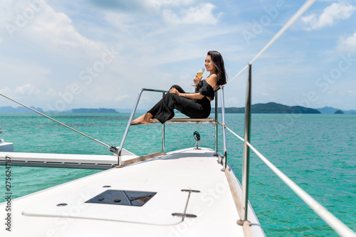 Luxury woman in evening black dress drinking champagne on the deck of a boat
