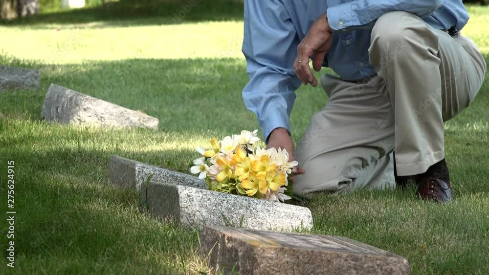 Man placing flowers on a grave, medium shot