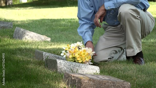 Man placing flowers on a grave, medium shot
