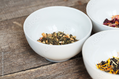 Aromatic dry tea in bowls on wooden background