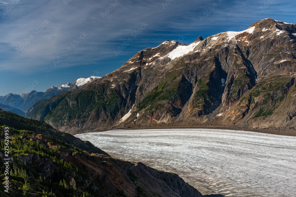 A view of the majestic Salmon Glacier as it dips down a gorge created by the the glacier in British Columbia, Canada, beautiful blue sky, nobody in the image