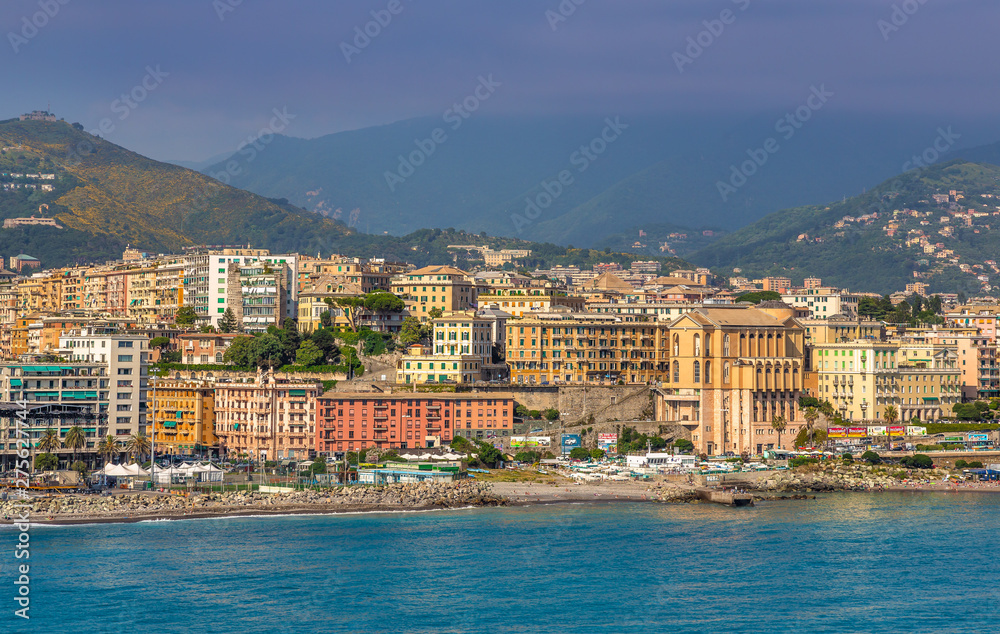 View of Genoa (Genova) from the port when arriving by ship, at sunrise with its yachts and vessels along the water.