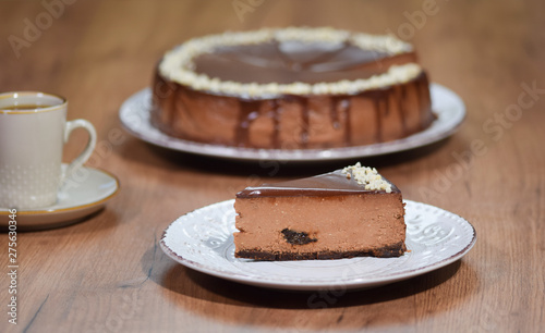 Chocolate cheesecake with hazelnuts. A slice of a chocolate cheese cake on a wooden background