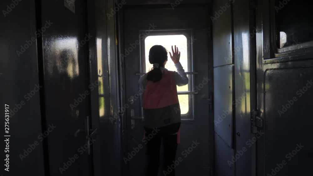 little teenage girl is a backpacker traveling by train. travel transportation lifestyle railroad concept. tourist school girl in the train wagon with backpack looking out the window waving his hand little teenage girl is a backpacker traveling by train. travel transportation lifestyle railroad concept. tourist school girl in the train wagon with backpack looking out the window waving his hand