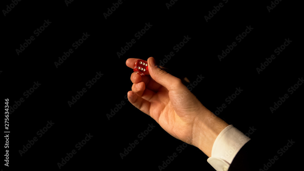Fototapeta premium Hand showing dice against black background, risk and success in gambling, casino