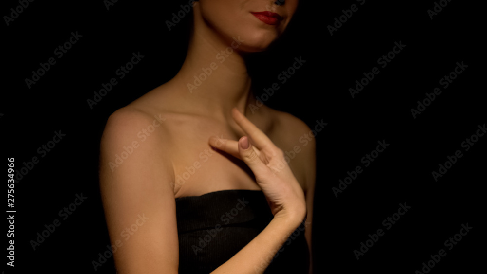 Flirty woman stroking her body isolated on dark background, prostitution concept Flirty woman stroking her body isolated on dark background, prostitution concept