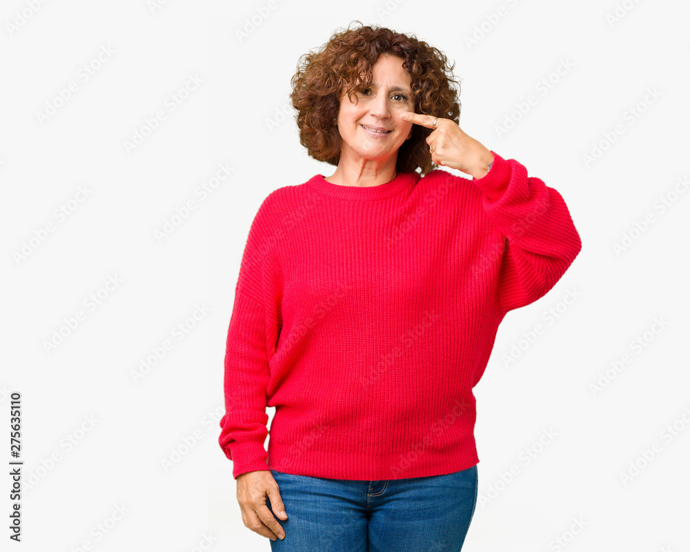 Beautiful middle ager senior woman red winter sweater over isolated background Pointing with hand finger to face and nose, smiling cheerful