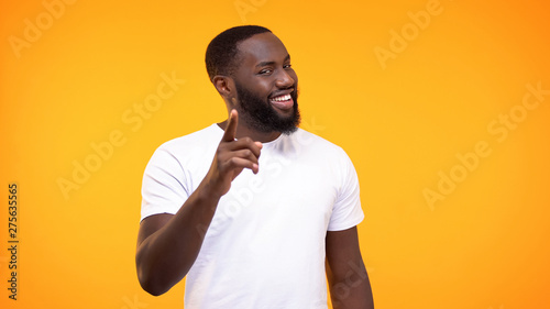 Fényképezés Smug afro-american man pointing finger camera and smiling yellow background