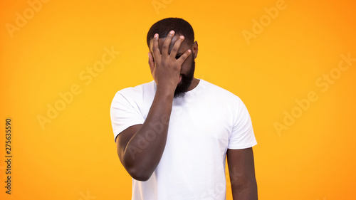 Disappointed afro-american male doing face palm gesture on yellow background