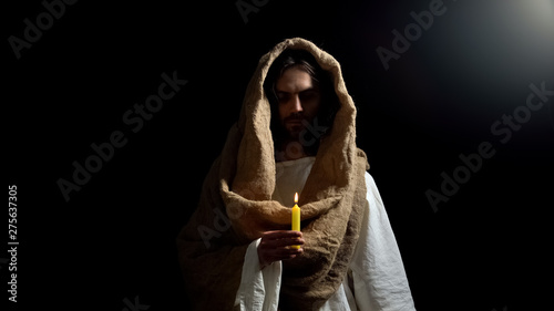 Messiah holding candle, praying for people sins expiation, belief and kindness photo