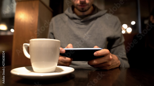 Young male scrolling smartphone in cafe  surfing internet  gadget addiction