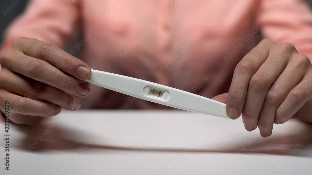 Female holding positive pregnancy test in hands, family planning, decision