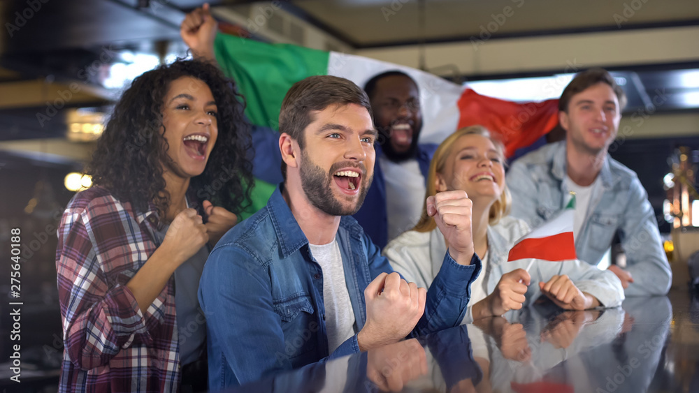 Obraz premium Cheerful Italian fans holding flag celebrating winning match, happy time in bar