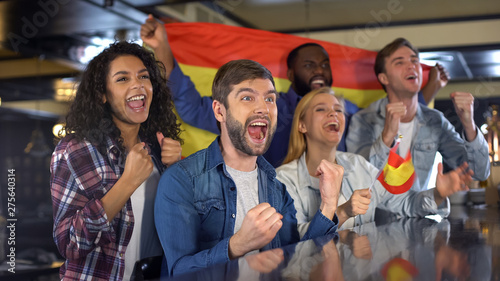 Extremely happy Spanish supporters waving national flag, celebrating victory