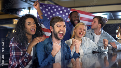 Excited sport fans with American flag celebrating victory of national team