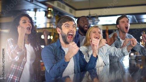 Extremely happy sport fans actively cheering team, celebrating victory in bar photo